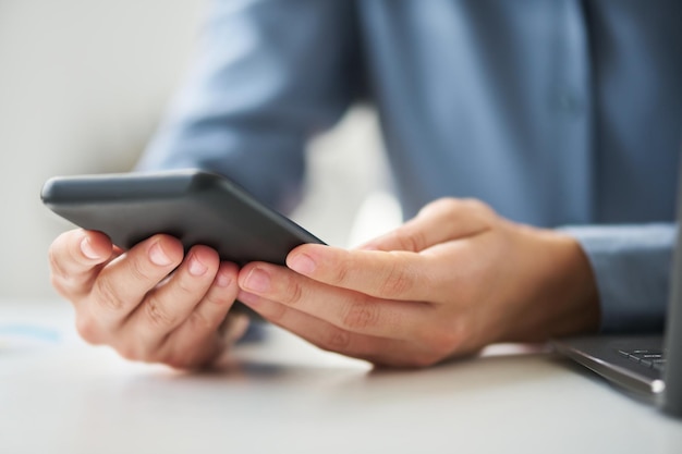 Closeup of hands of young modern white collar worker with mobile phone