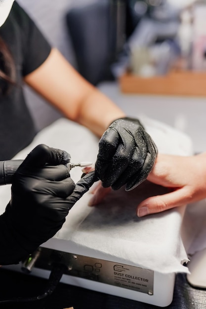 Photo closeup of the hands of a young woman receiving the nail file by a beautician at the beauty salon