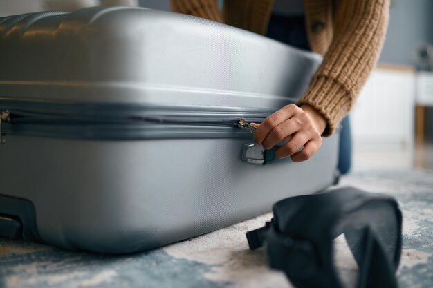 Closeup of hands zipping travel suitcase luggage. Packing belongings for trip and holiday vacation