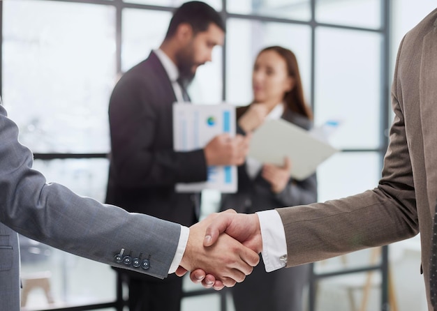 Closeup of a handshake of business partners against the background of colleagues