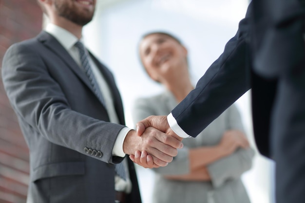 Closeup of handshake of business partners on the background of business team