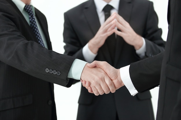 ボケ味の背景に対して撮影されたビジネススーツを着ている2人の起業家の握手のクローズアップ