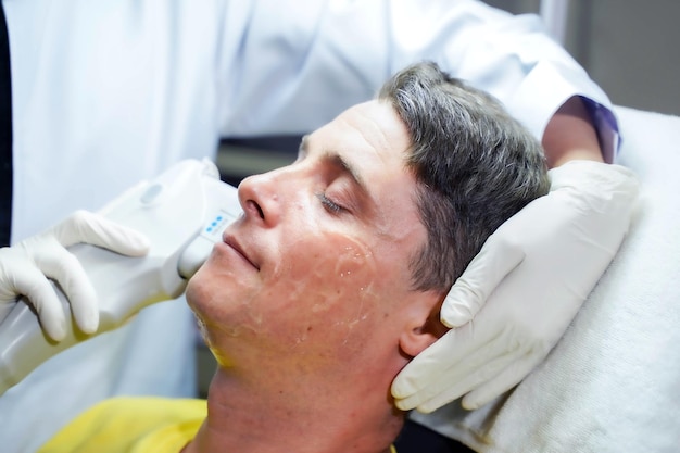Крупный план красивого мужчины, проходящего цветотерапию для стимуляции кожи лица