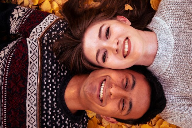 Photo closeup of happy couple lying on leaves