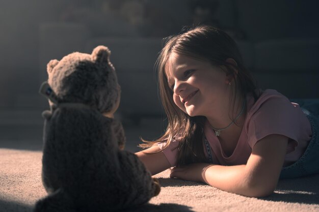 Photo closeup of happy little girl playing with teddy bear