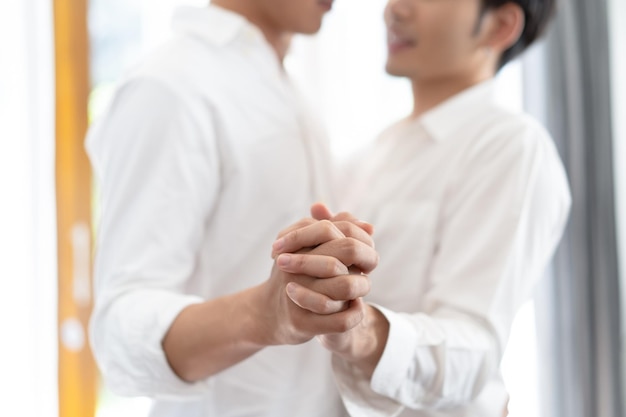 Closeup of happy male gay couple holding hands and dancing in the living roomfocus on hands