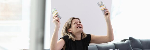 Foto close-up di una donna felice e sorridente che tiene pile di banconote da un dollaro e una valigia piena di soldi