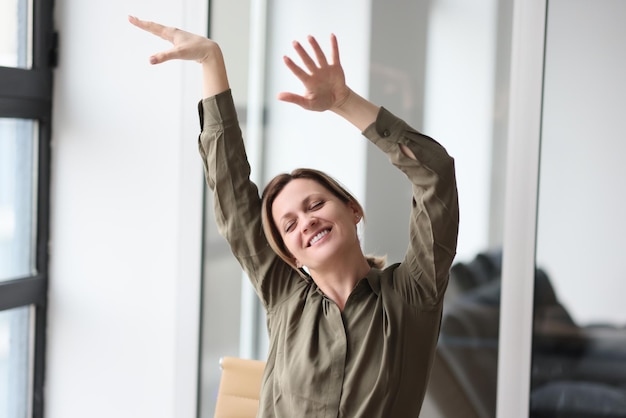 Closeup of happy woman manager raising hands up and celebrating victory in office success in