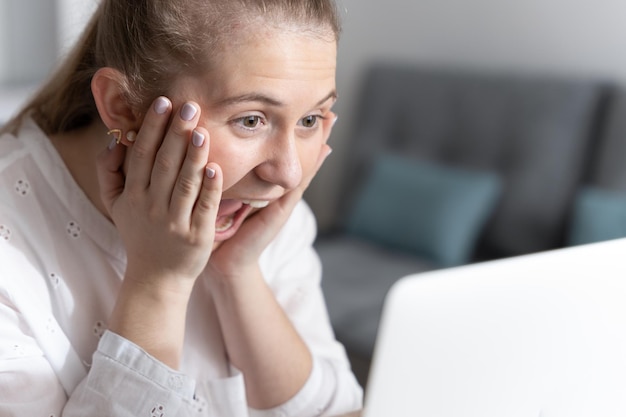 Closeup of happy young woman hands on face in front of laptop