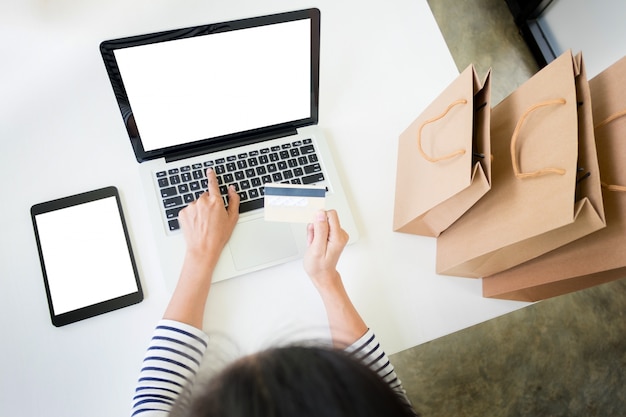 Closeup of happy young woman holding credit card inputting card information while and using laptop computer at home. Online shopping concept.