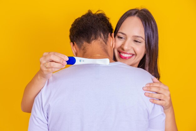 Closeup of happy young woman hugging man after positive pregnancy test