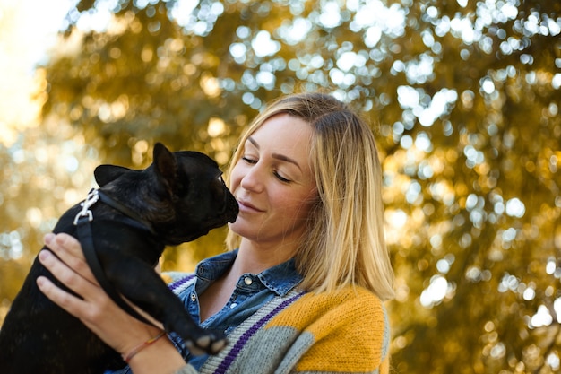 秋の屋外で犬と幸せな若い女性のクローズアップ