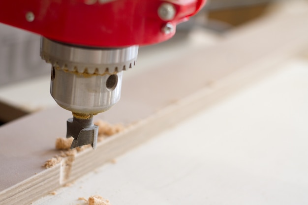 Closeup of the head of the drilling machine with nozzle in the furniture workshop