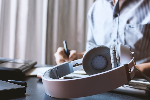 Closeup headphones and businessman  working on laptop In office 