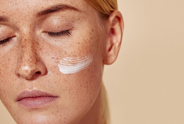 Closeup high detailed cropped shot of a young female with moisturizer on her cheek