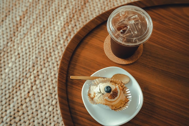 Closeup of Homemade white orange cake and Americano iced coffee or black coffee in wood desk office desk in coffee shop at the cafe in gardenduring business work concept