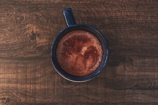 Closeup of hot cocoa drink in blue mug on wooden table