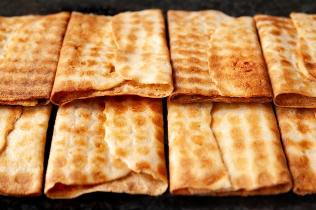 A closeup of hot crispy cookies stacked in a row on black marble Freshly baked cookies