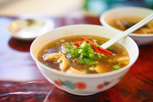 Closeup of hot and sour soup with vibrant red broth