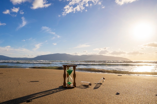 Closeup of hourglass on the sandtimer beach sunset