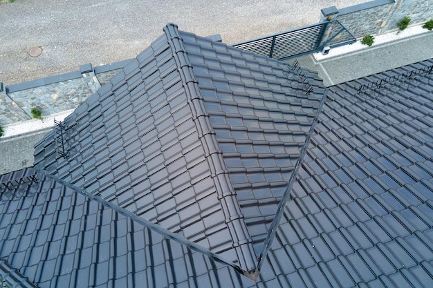 Closeup of house roof top covered with shiny ceramic shingles.