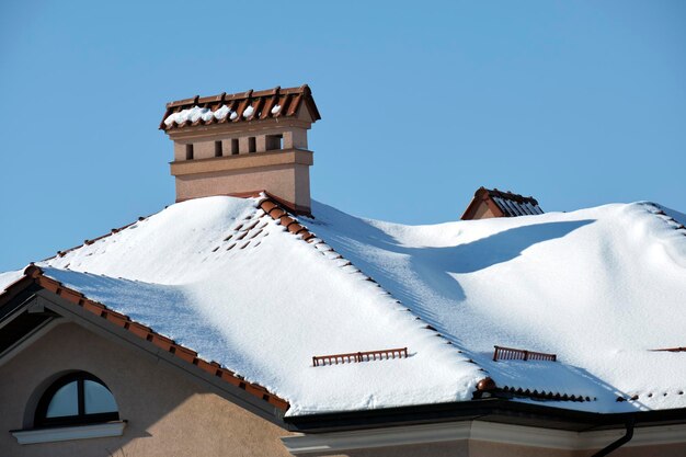 Closeup of house roof top covered with snow in cold winter\
tiled covering of building in wintertime weather