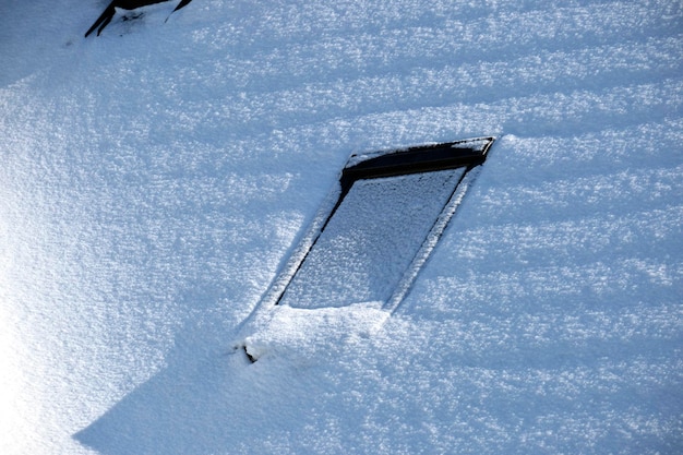 Closeup of house roof top with attic windows covered with snow in cold winter Tiled covering of building in wintertime weather