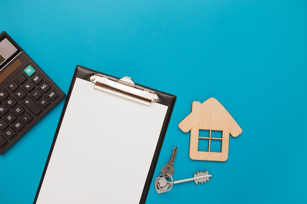 Closeup of house wooden model and keys with blank for text on blue