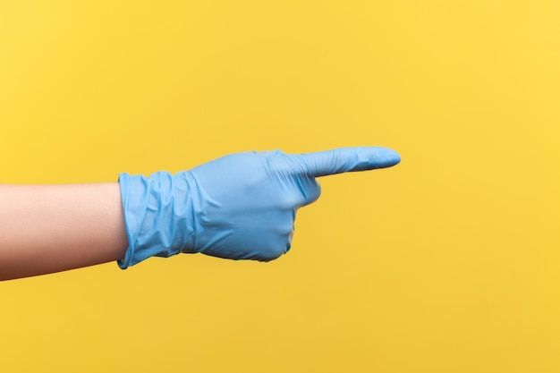 Closeup of human hand in blue surgical gloves showing or pointing ot something with finger.