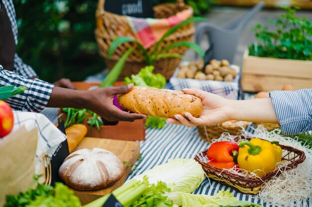 Closeup of human hands taking bread from salesman at farm market