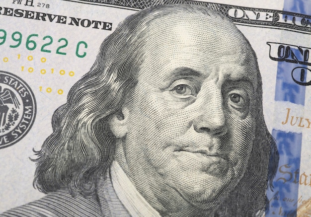 Closeup of a hundred dollars bill showing Benjamin Franklin.