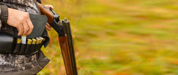 Closeup of a hunter holding a gun in his hands a leather bandolier with cartridges on his belt Process of hunting during season Selective focus