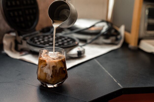 カフェの黒いテーブルで提供されるアイスコーヒーのクローズアップ