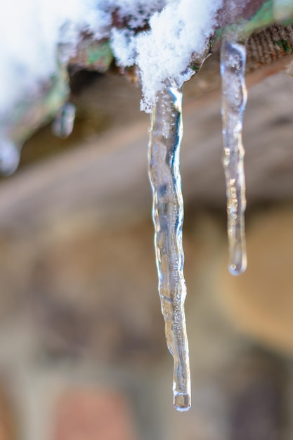 家の屋根の上の氷を暖め、溶かしながらつららのクローズアップ