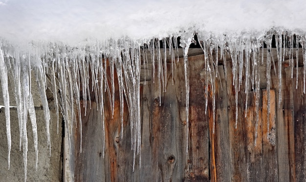 Closeup on icicles forming on a wooden wall of a chalet