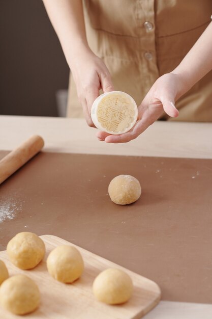 Primo piano immagine della donna che mostra la forma di plastica che sta usando per fare il mooncake per la celebrazione di metà autunno