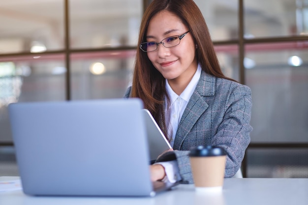 Крупный план азиатской деловой женщины, использующей цифровой планшет и портативный компьютер в офисе