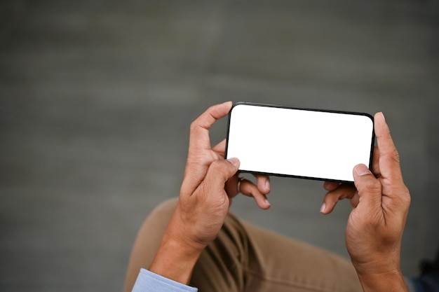 Closeup image of an Asian man playing mobile games or watching videos on his smartphone