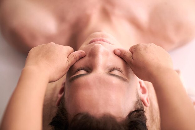 Closeup image of beautician massaging face of man to stimulate collagen production