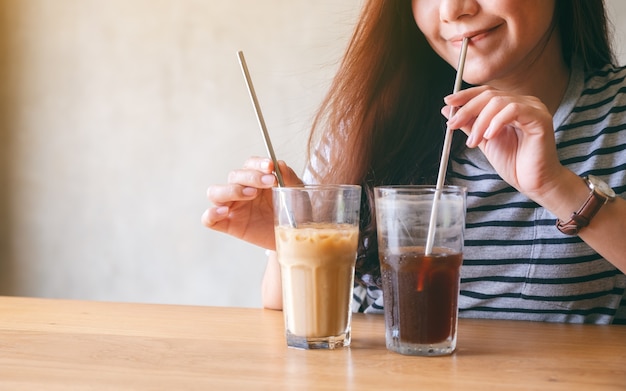 Closeup image of a beautiful asian woman drinking iced coffee with stainless steel straw