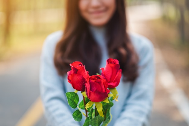 발렌타인 데이에 빨간 장미 꽃을 들고 주는 아름다운 아시아 여성의 클로즈업 이미지