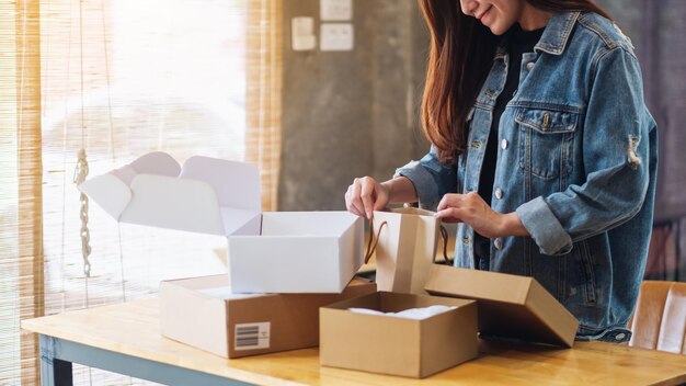 Closeup image of a beautiful asian woman opening and looking inside shopping bag at home for delivery and online shopping concept