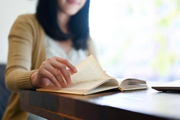 Closeup image A beautiful Asian woman reading a book while relaxing in the coffee shop