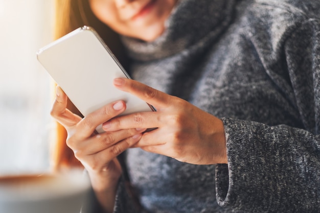 Closeup image of a beautiful woman holding and using mobile phone