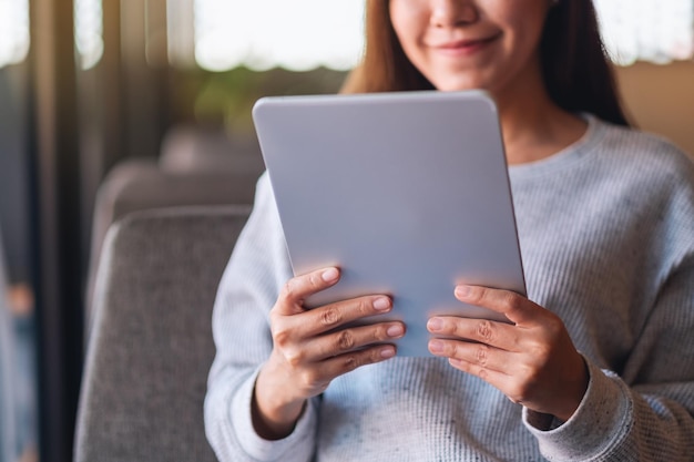 Closeup image of a beautiful young asian woman holding and using digital tablet