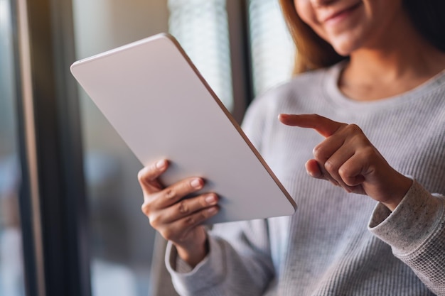 Closeup image of a beautiful young asian woman holding and using digital tablet