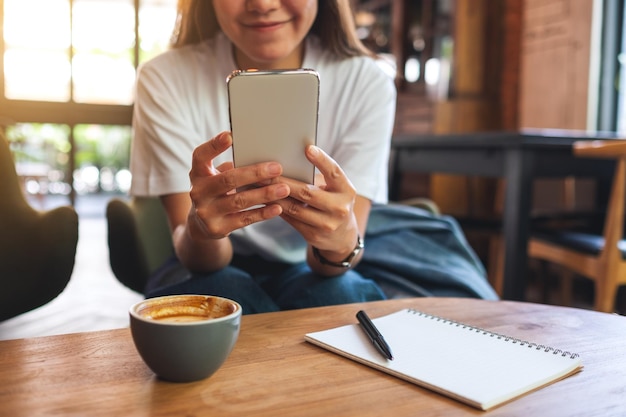 Closeup image of a beautiful young asian woman holding and using mobile phone