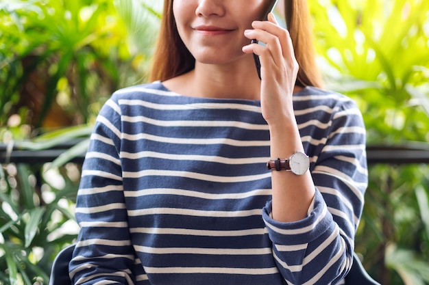 Photo closeup image of a beautiful young asian woman talking on mobile phone