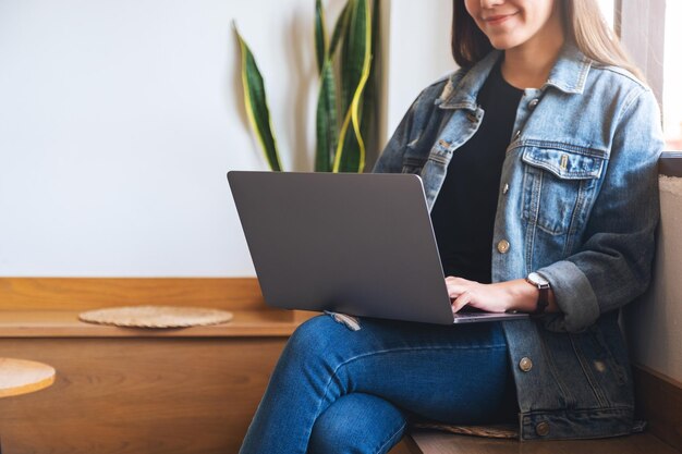 Closeup image of a beautiful young asian woman working and typing on laptop computer