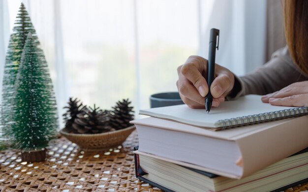 Closeup image of a beautiful young asian woman writing on notebook while study at home